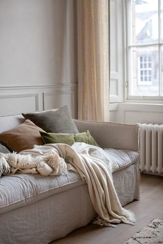 an unmade bed sitting in front of a window next to a radiator