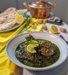 a white plate topped with meat covered in pesto next to a pot of food