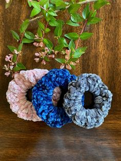 three crocheted scrunffles sitting on top of a wooden table next to a plant