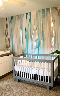 a baby's crib in front of a painted wall with blue and white paint