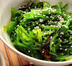 a white bowl filled with green vegetables on top of a wooden table