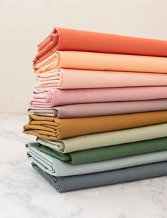 a stack of folded sheets sitting on top of a marble countertop next to each other