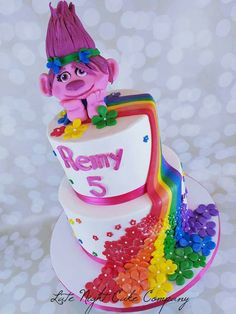 a birthday cake with a troll on top and rainbow sprinkles around it