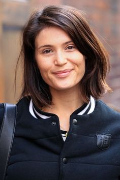 a close up of a person wearing a black jacket and smiling at the camera with a smile on her face