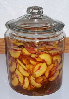 a jar filled with sliced peaches sitting on top of a table next to a wall