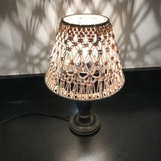 a lamp that is on top of a table with a shadow cast on the wall behind it