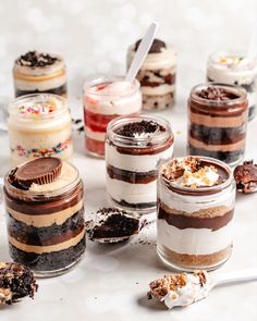 there are many desserts in glass jars on the table