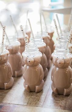 there are many little teddy bears in the cups on the table with straws sticking out of them