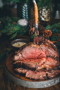 a roasting pot roast is sitting on a table with pine cones and other holiday decorations