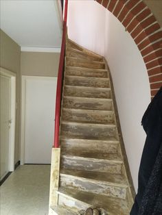 a wooden stair case next to a brick wall