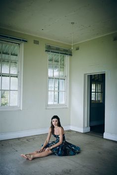 a woman sitting on the floor in an empty room