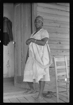 an old photo of a woman standing in front of a door with a towel over her shoulder