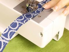 someone is using a sewing machine to sew on a blue and white tie that's being made