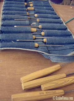 several pairs of wooden knitting needles on top of blue jeans