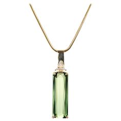 Green cylinder tourmaline and trilliant cut accent diamond. 14k yellow gold pendant necklace, made in the Peter Suchy Workshop. 1 cylinder green VS tourmaline, Approximate 17.9cts 1 trilliant cut J SI2 diamond, Approximate .32cts 14k yellow gold Stamped: 14k 13.3 grams Top to Bottom: 42.87mm or 1 5/8 Inches Width: 1.2mm or 3/8 Inch Depth or Thickness: 8.1mm Chain: 16 Inches 1.5mm square snake chain Formal Green Tourmaline Necklace, Round Diamond Pendant, White Gold Pendant Necklace, Vintage Pendant Necklace, Art Nouveau Pendant, Diamond Collection, Tourmaline Pendant, Hot Jewelry, Tourmaline Necklace