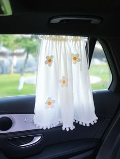 a car with a white curtain hanging from it's side window and flowers on the front