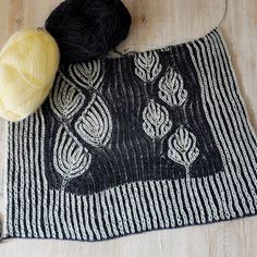 two balls of yarn sitting on top of a black and white rug next to a ball of yarn