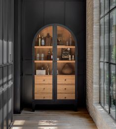 an arched glass door leads into a room with black walls and wooden furniture, along with windows