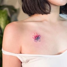 a woman with a pink flower tattoo on her left shoulder and chest, looking at the camera