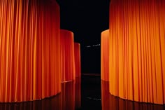 an orange curtain is in the middle of a dark room