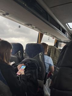 people sitting in the back of a bus looking at their cell phones