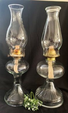 two clear glass vases sitting next to each other on top of a black cloth