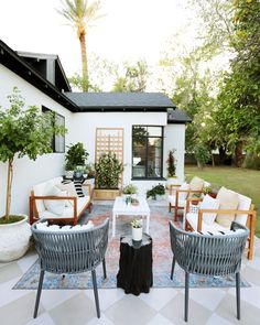 an outdoor living area with wicker furniture and potted plants on the side of the house