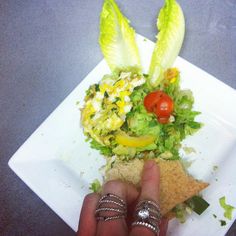 a person is holding their finger over a plate with food on it, including lettuce and tomatoes