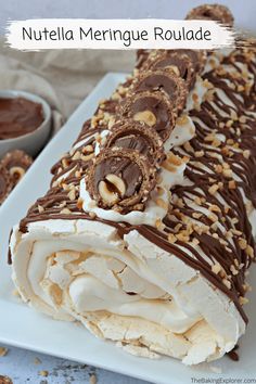 nutella meringue roulade on a white plate with chocolate drizzle and nuts