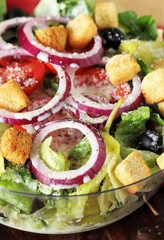 a salad with onions, lettuce, tomatoes and croutons in it