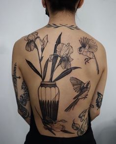 a woman with tattoos on her back has flowers in a vase and birds flying around