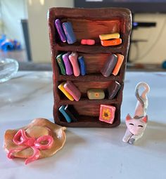 there is a small toy cat next to a wooden shelf with magnets on it