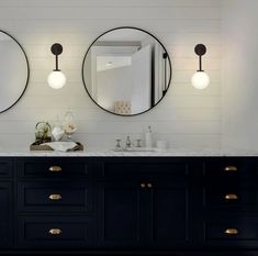 a bathroom with two round mirrors on the wall and double sinks in front of it