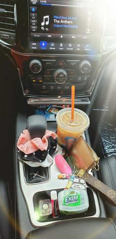 the interior of a car with various items in it, such as a drink and music player