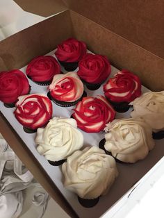 a box filled with cupcakes covered in red and white frosting