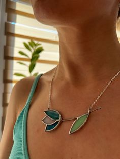 a woman wearing a necklace with two leaves on the front and one leaf on the back