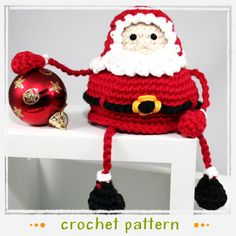 a knitted santa clause sitting on top of a white shelf