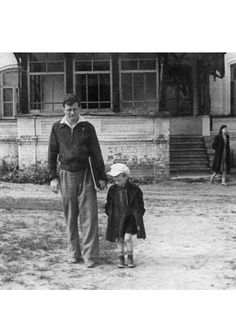 an old black and white photo of a man walking with a child