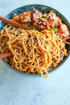 a bowl filled with noodles, meat and sesame seeds