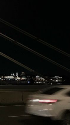 a blurry photo of a car driving down the road at night with city lights in the background