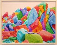 an abstract painting with multicolored rocks in the foreground and a white frame around it