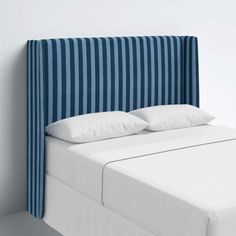 a bed with blue and white striped headboard next to a wall in a room