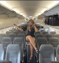 a woman sitting on the back of an airplane with her legs crossed and one hand up