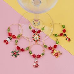 several wine glasses with charms on them sitting next to each other in front of a yellow and pink background