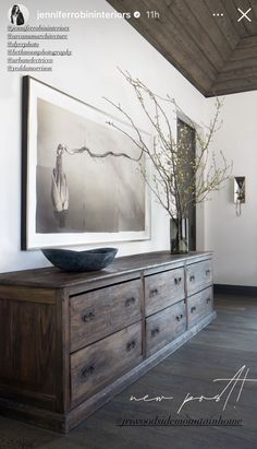 a wooden dresser sitting next to a painting on the wall