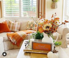 a living room filled with white furniture and lots of fall decor on top of it