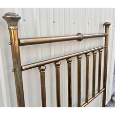 a close up of a metal bed frame with brass colored posts and knobs on the headboard