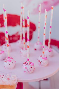 cake pops with sprinkles and pink frosting are arranged on a table