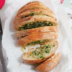 a loaf of bread with pesto and cheese on it next to a knife, fork and napkin