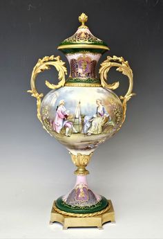 an ornate vase with figures painted on the sides and gold trimming around the base